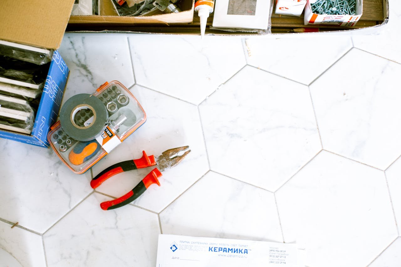 A selection of home renovation tools placed on a white tiled floor, ready for use.